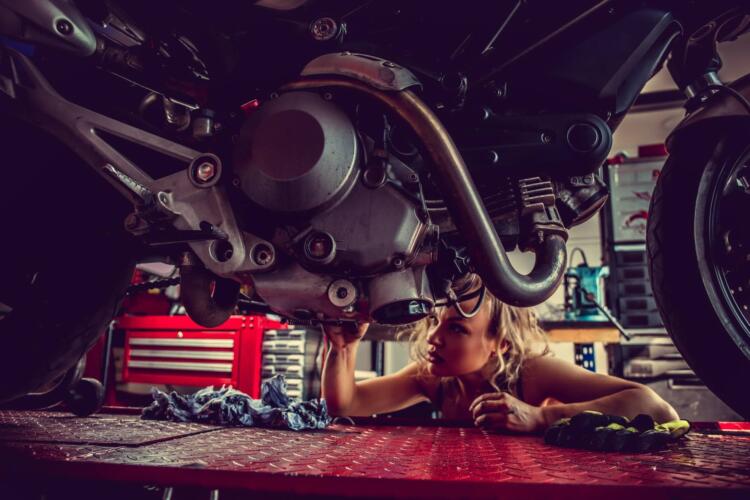 Blond woman repairing motorcycle.
