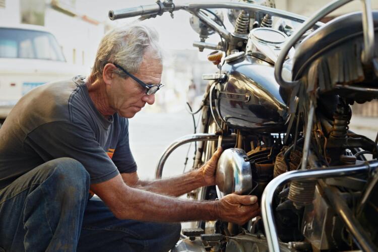 Senior Man Fixing Vintage Motorcycle Engine