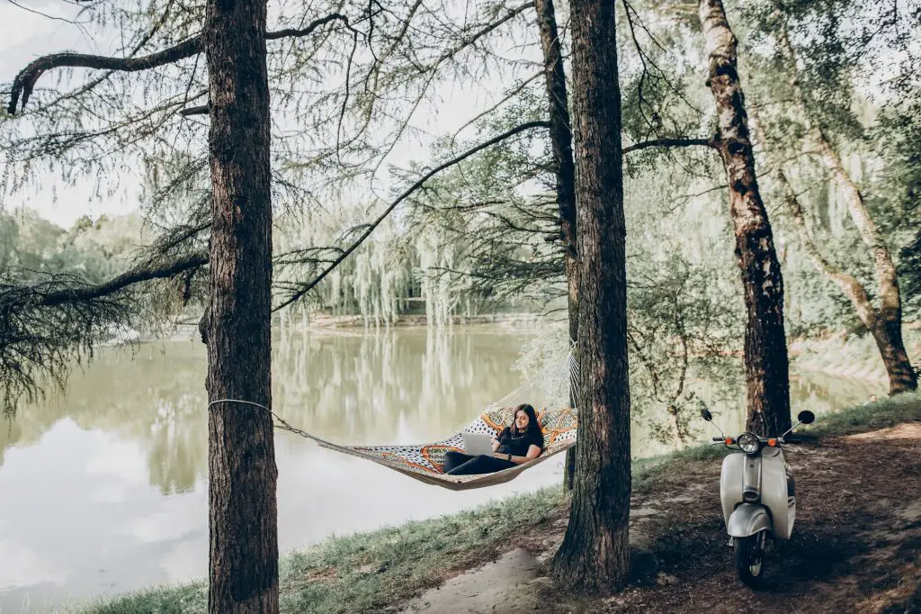 Freelancer working in the park while resting in hammock