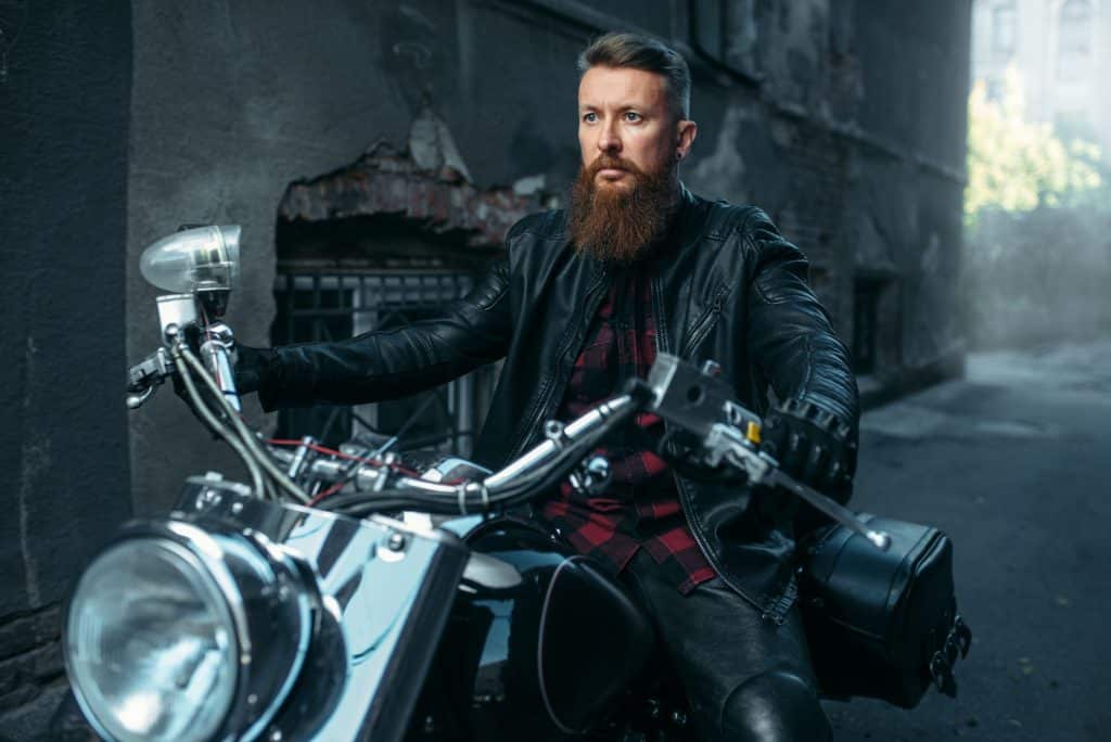 Motorcyclist in leather jacket poses on chopper