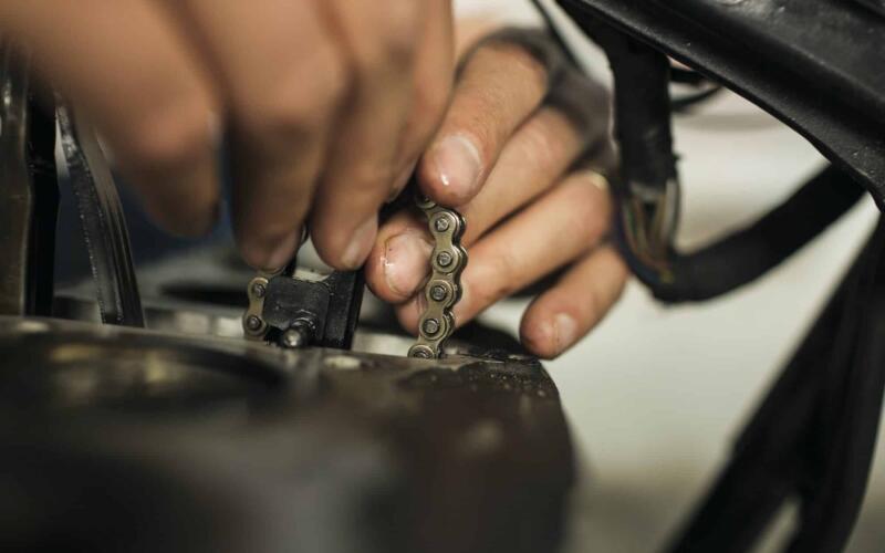 Close up of man holding chain during repair of motorcycle