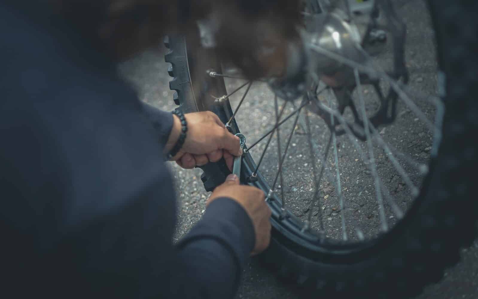 person in black jacket holding bicycle wheel