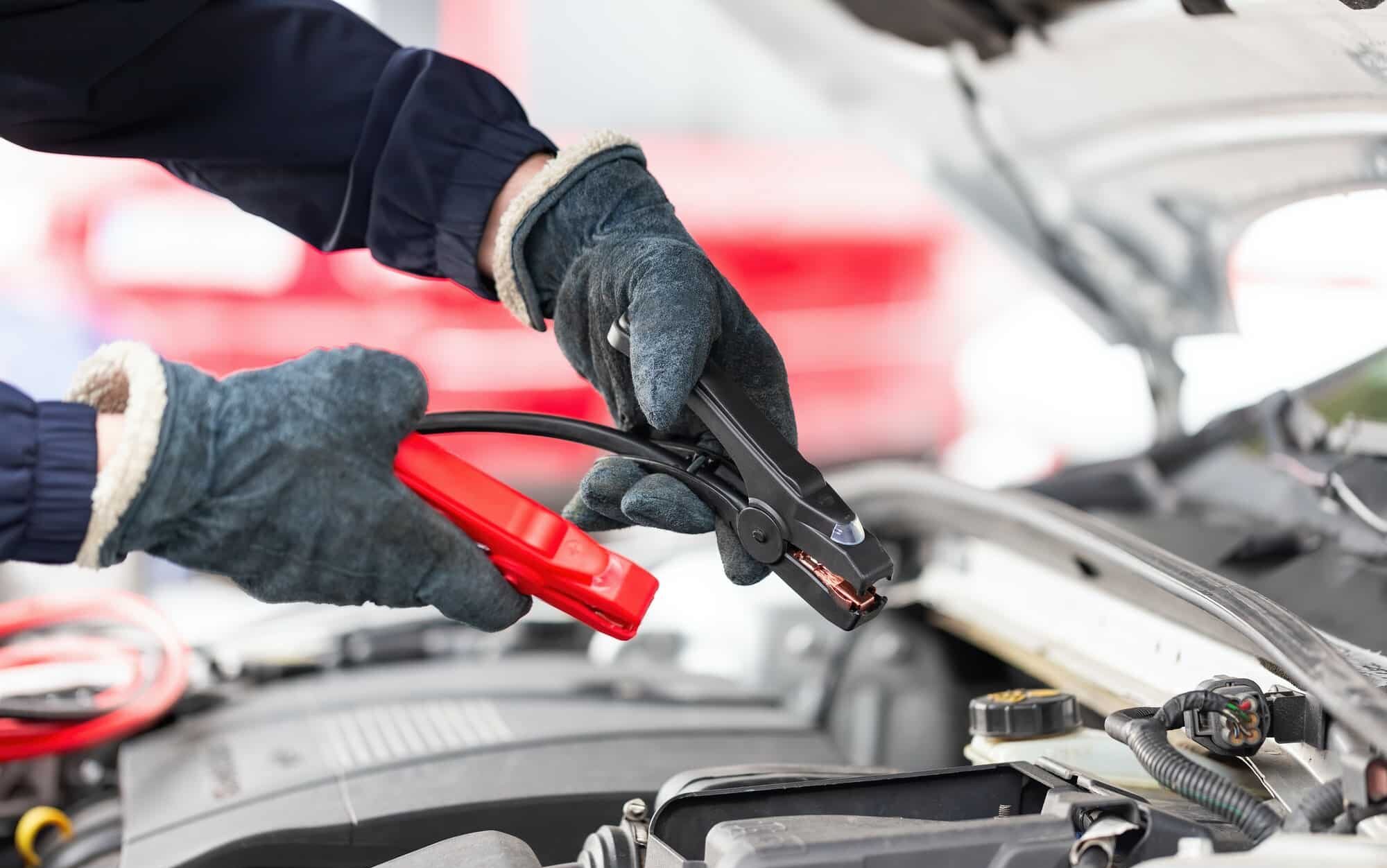 Human trying to start engine with jumper cables in close up