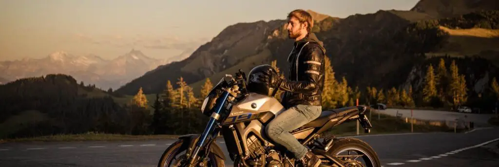 man in brown jacket riding on white and black motorcycle