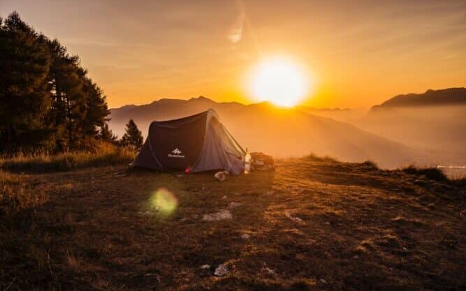 dome tent on mountain top with sun as background photo